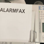 Faxgerät mit Blatt auf dem Alarmfax steht.