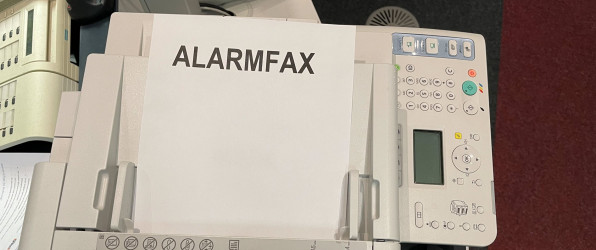 Faxgerät mit Blatt auf dem Alarmfax steht.