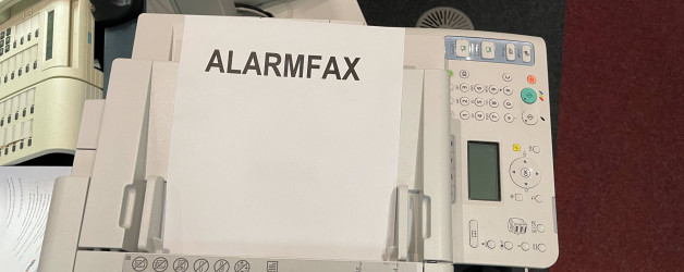 Faxgerät mit Blatt auf dem Alarmfax steht.